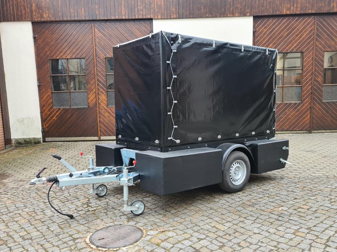 Der Prototyp Ein PKW Anhänger mit schwarzer Plane und eckigen Schwimmkörpern an der Seite